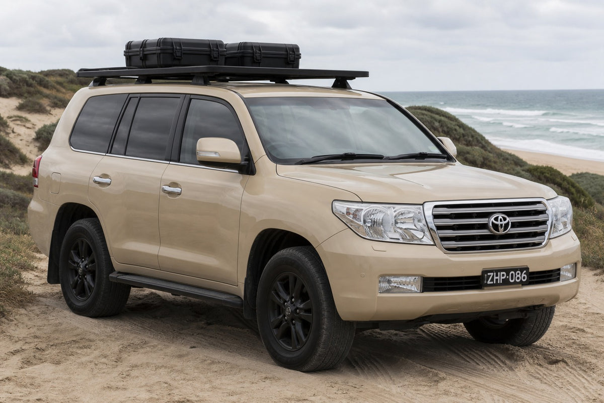 Tan Toyota LandCruiser 200 wagon with black Roar 4x4 platform roof rack fitted, front three-quarter, coastal dunes