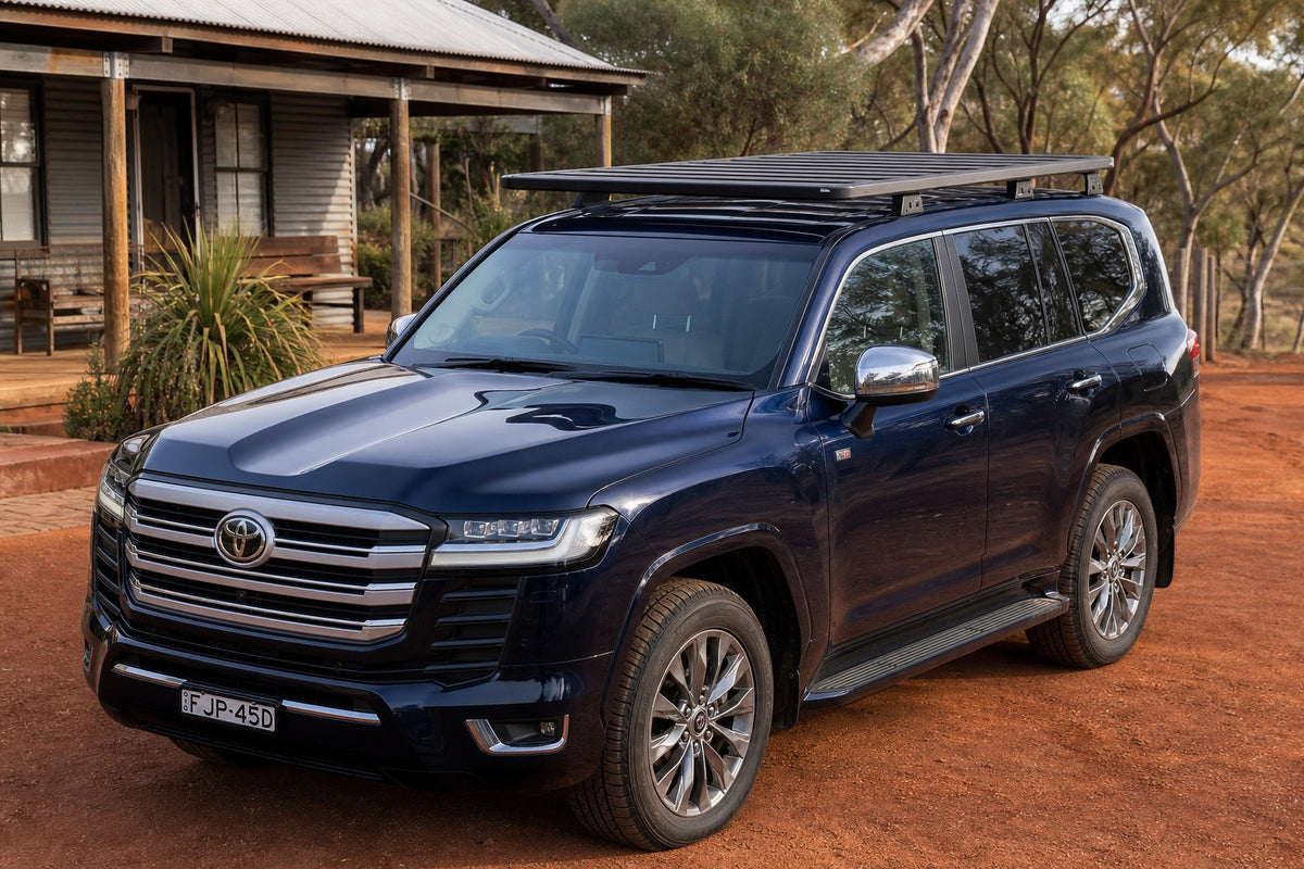 Navy Toyota LandCruiser 300 with black Roar 4x4 platform roof rack fitted, front three-quarter, rural red dirt